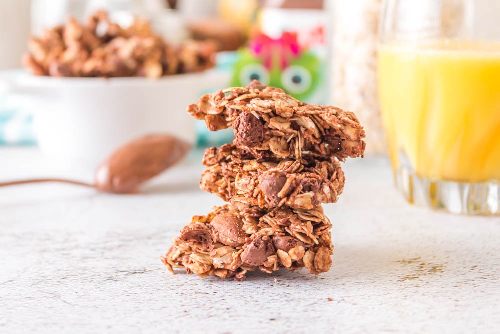 Kid-approved breakfast Nutella granola is done in under an hour in the air fryer. Three big clusters are staked up where you can see the chocolate chips and almonds.