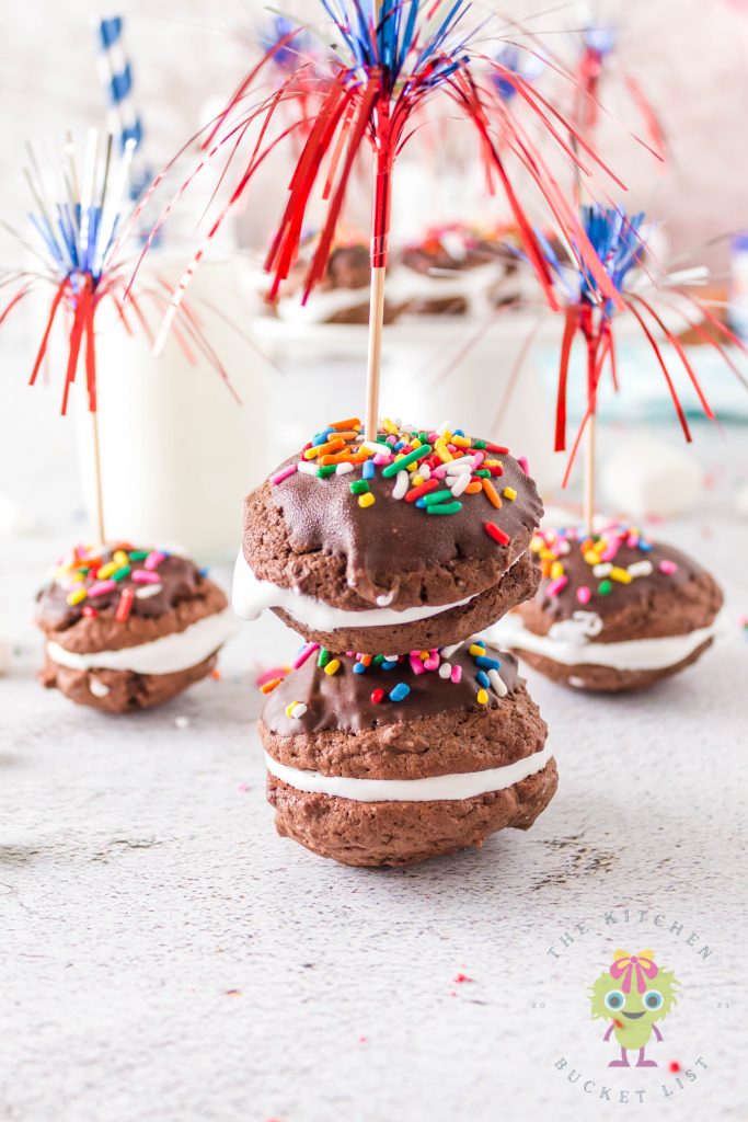 Two sandwich cookies stacked in front and more cookies in the back