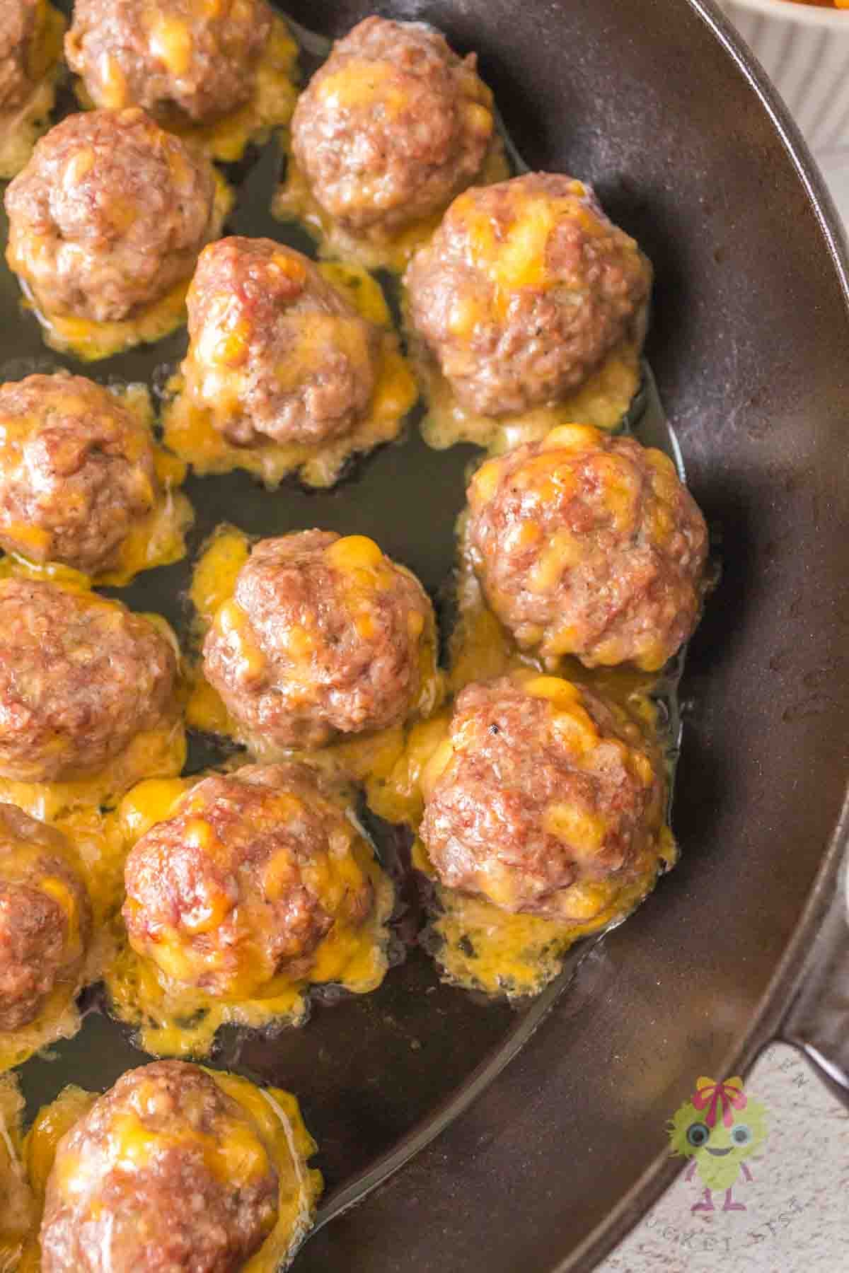 A close-up of the smoked meatballs in the cast iron pan with the cheese melting.