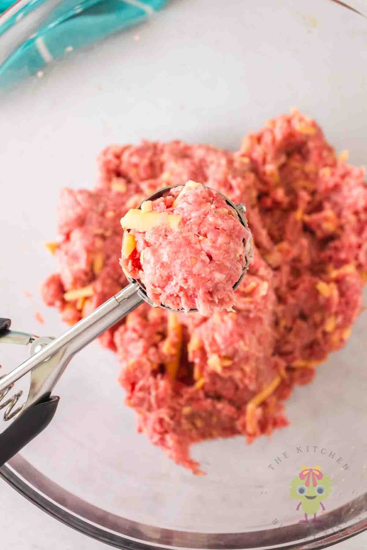 Close-up of using a medium cookie scoop to shape these BBQ meatballs.