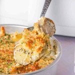 Serving scalloped potatoes from the air fryer with a spoon. The side dish has a cheesy-crunchy crust.