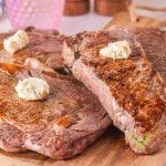 A cutting board filled with the ribeye and New York strip steaks with a golden sear and cooked to a perfect medium rare temperature.