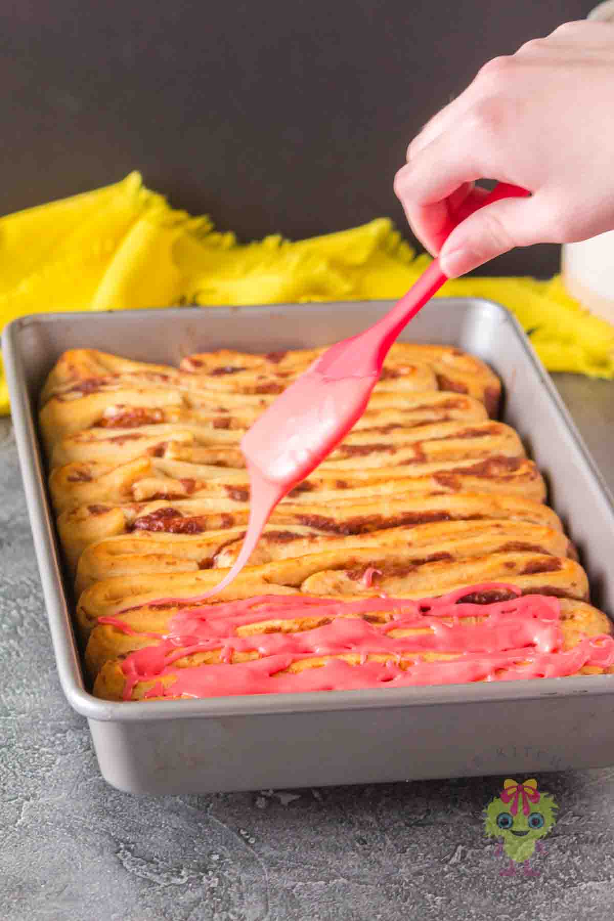 Drizzling glaze over the baked Pillsbury dough to add the perfect touch of gore and give that intestine look.