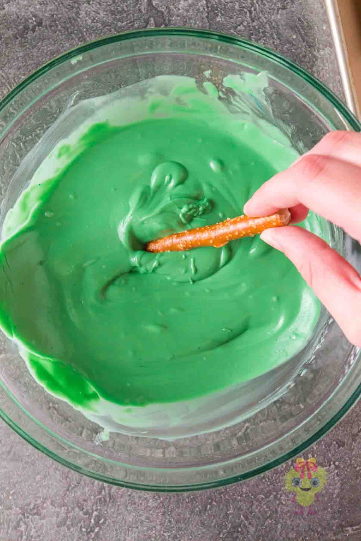 Coat the pretzel rods with melted chocolate by dipping them in the bowl.