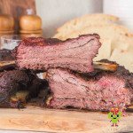 Two ribs with a red smoke ring and dark mahogany bark stacked on each other.