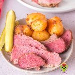 Sliced corned beef with roasted potatoes and sliced pickles ready to be enjoyed.