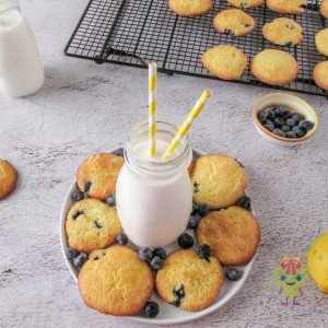 A plate of lemon blueberry cookies with with a glass of milk in the middle, ready to be enjoyed.
