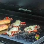 Showing how the griddle is a "one-spot wonder" for making the Philly cheesesteaks. You see how the grilled shaved ribeye steak and veggies with melted provolone has been divided ready to be put into the grilled hot dog buns next to them.