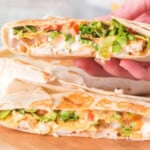 Time to enjoy a chicken crunchwrap. It is sliced in half and in a hand ready to eat.