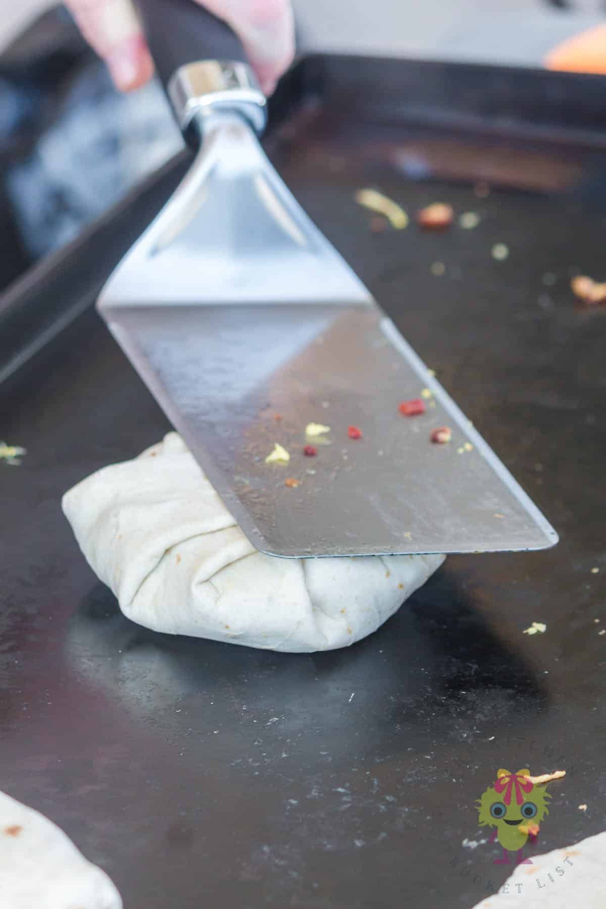 Pressing the folds with the spatula to set them.