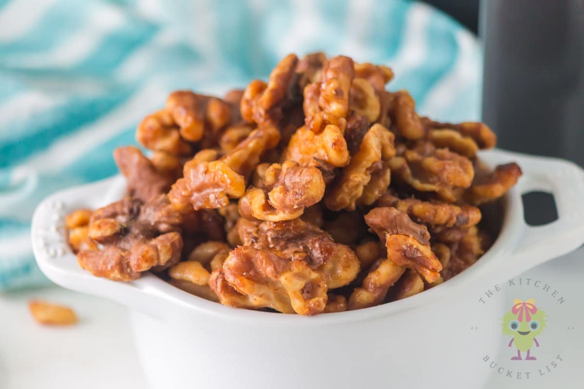 Roasted walnuts coated with honey and cinnamon in a white serving bowl, ready to be enjoyed.