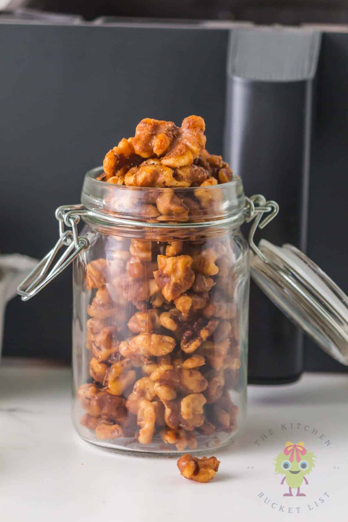 Honey glazed roasted walnuts cooled in a glass jar ready to be enjoyed as a snack or as a topping.