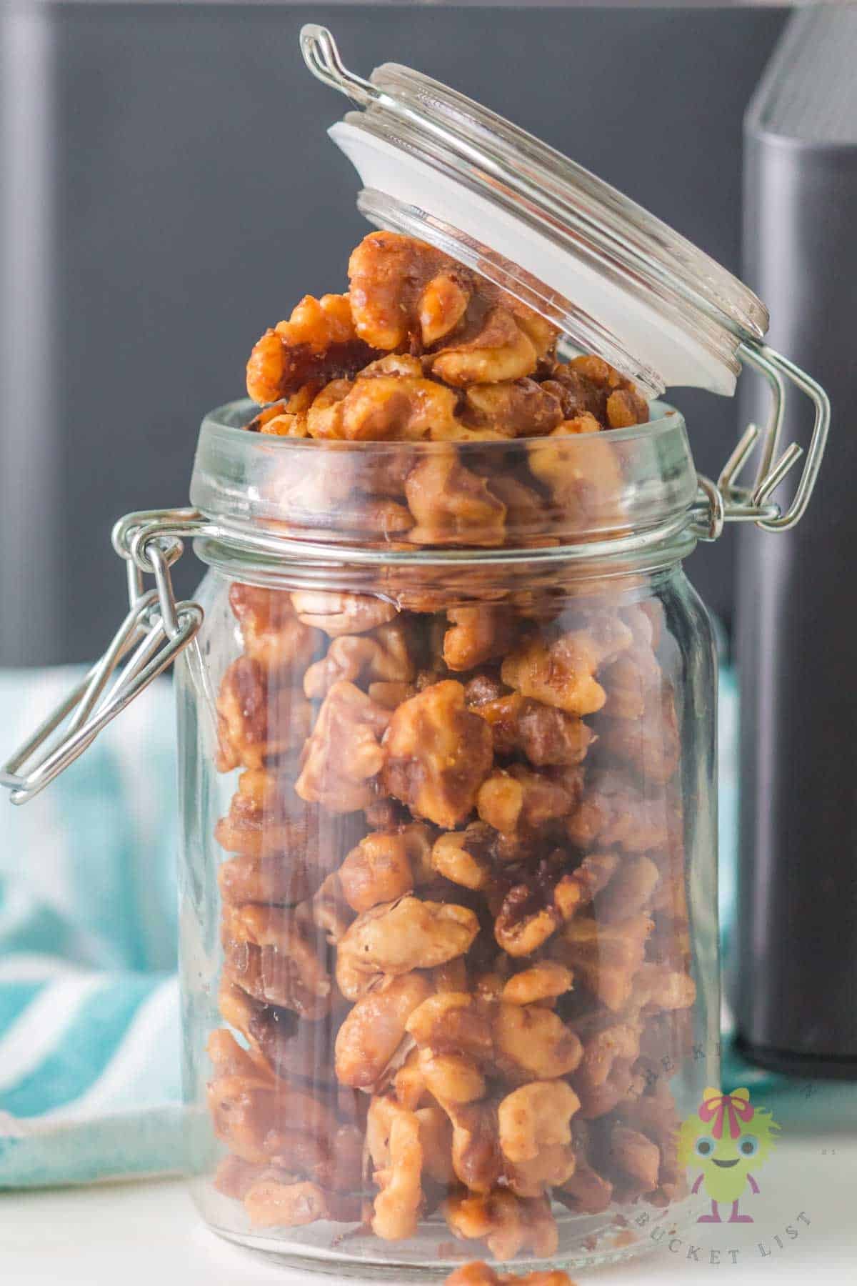Honey and cinnamon roasted walnuts cooled in a glass jar ready to be enjoyed as a snack or as a topping.