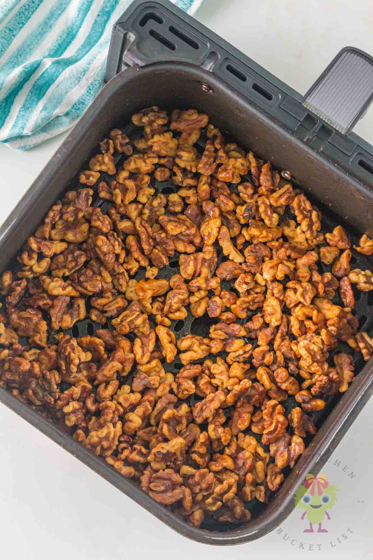 Golden toasted nuts in the bottom of the air fryer basket.