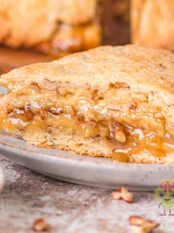 Pecan pie scone on a plate ready to enjoy. It has a perfect golden crust and in the middle is the pecan pie filling.