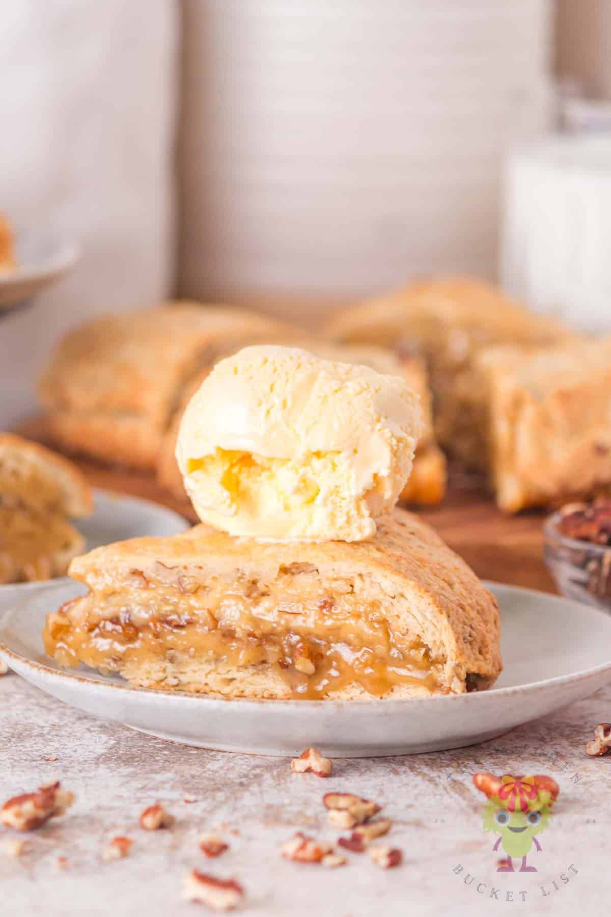 A piece of pecan pie scone with a scoop of vanilla ice cream on top.