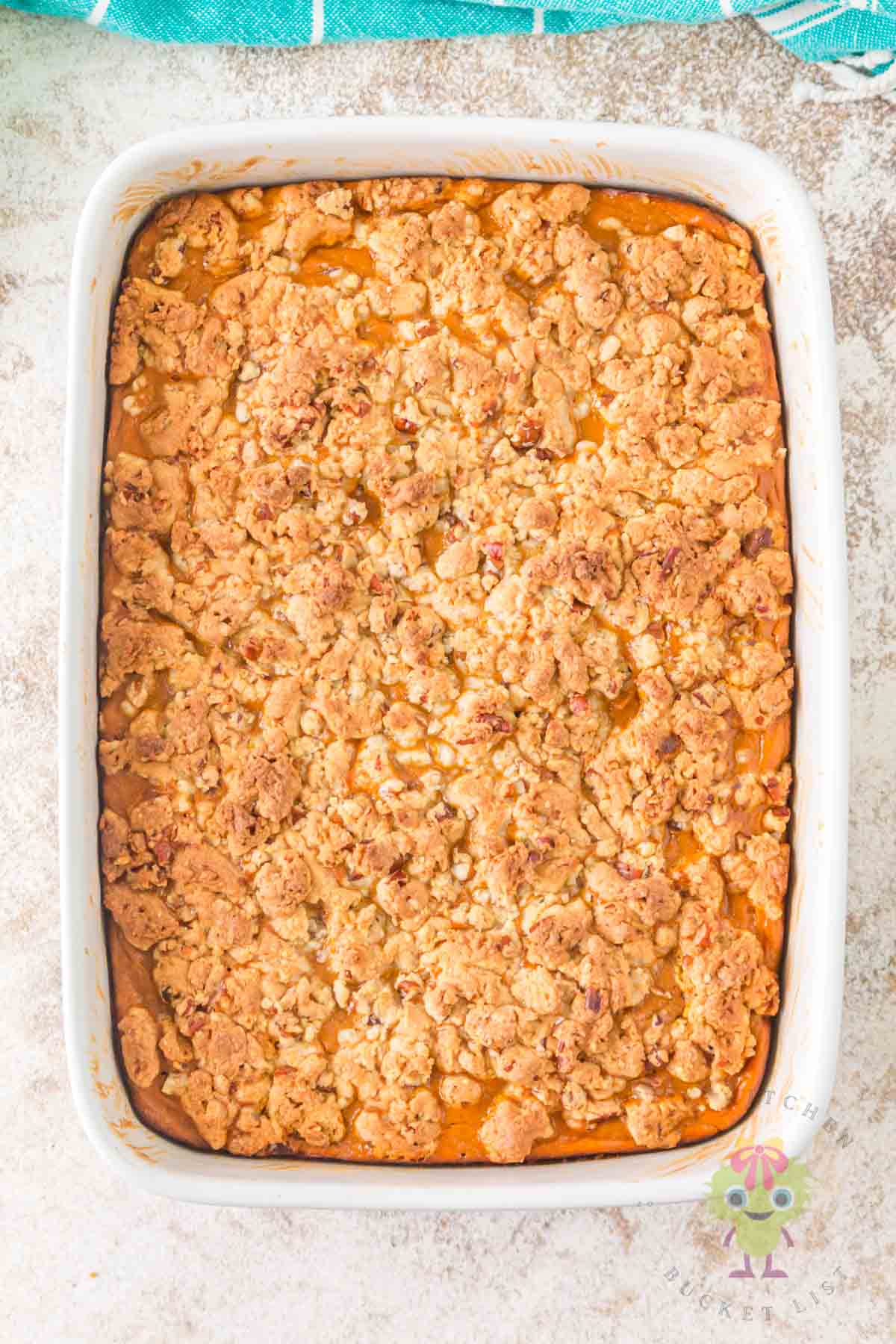 Beautifully baked pumpkin pie cake with its golden, crunchy pecan crumble. Little ribbons of the creamy pumpkin filling can be seen between the crumbles.
