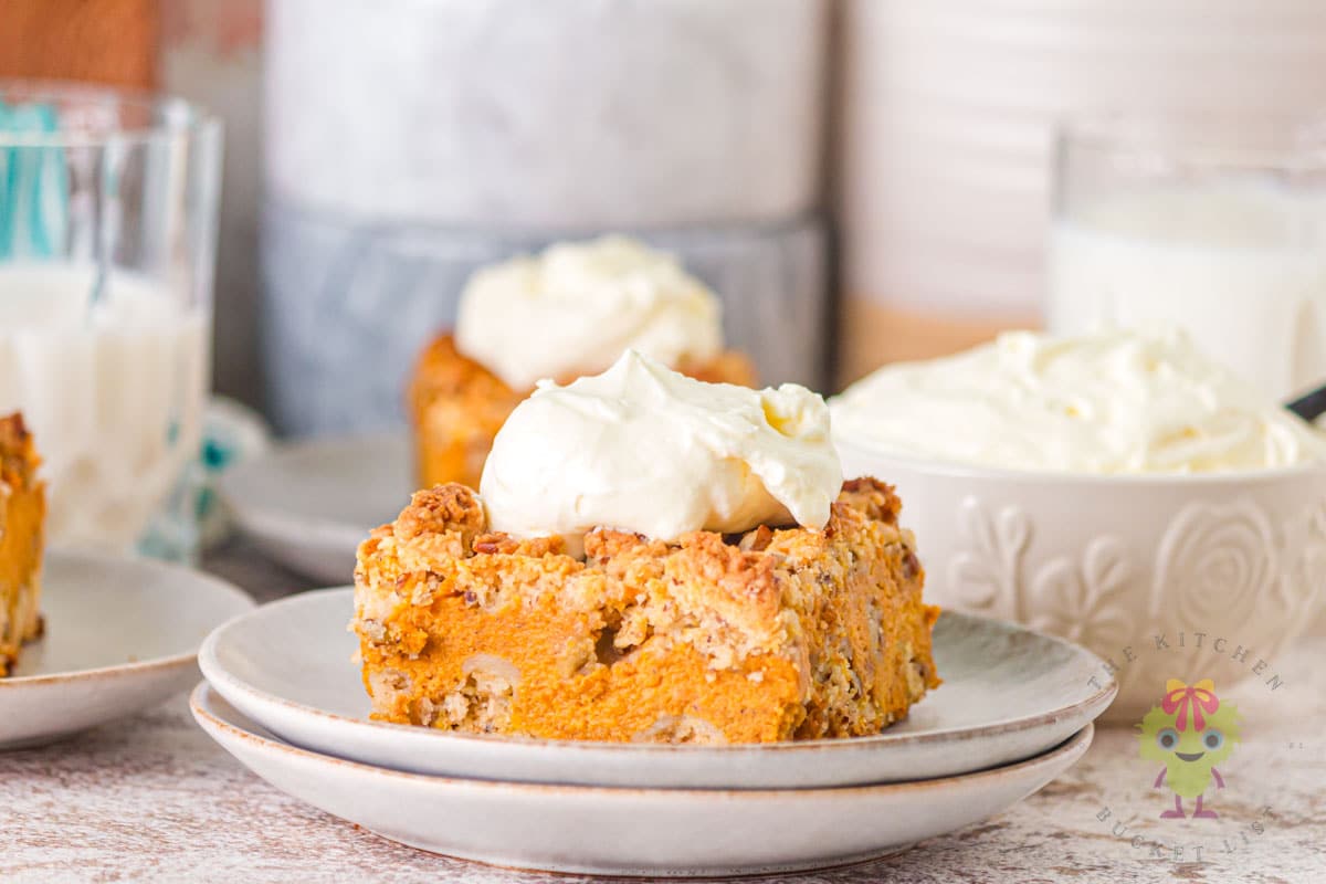 Pumpkin pie cake with homemade whipped cream, you can see the creaminess of the filling and the crunchy pecan topping.