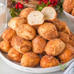 Cinnamon sugar pretzel bites arranged in a cozy holiday setting, with the top pretzel bite sliced open to show its soft, fluffy texture.