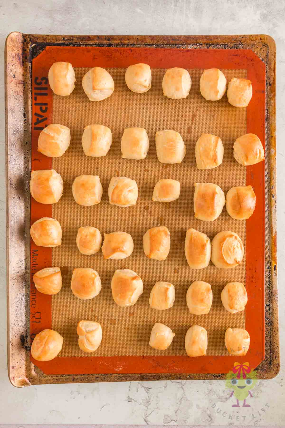 Freshly baked bite-sized pretzels on a baking sheet, golden brown and soft, straight from the oven.