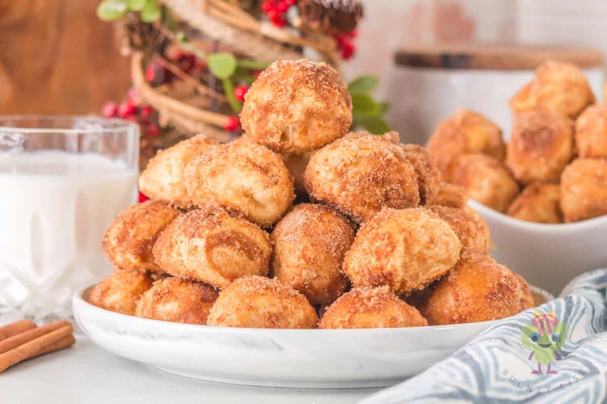 Golden, soft pretzel bites stacked on a serving plate with a festive holiday setting behind them.