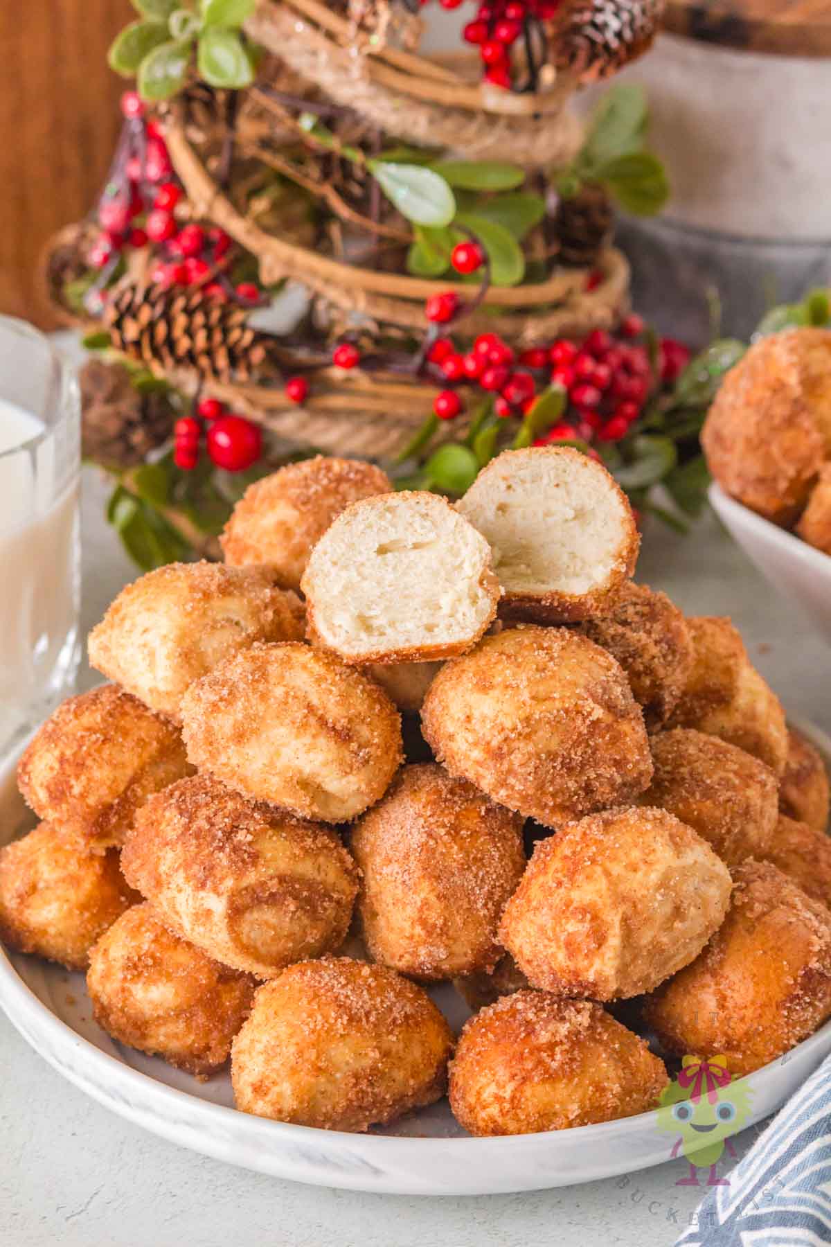 Cinnamon sugar pretzel bites arranged in a cozy holiday setting, with the top pretzel bite sliced open to show its soft, fluffy texture.
