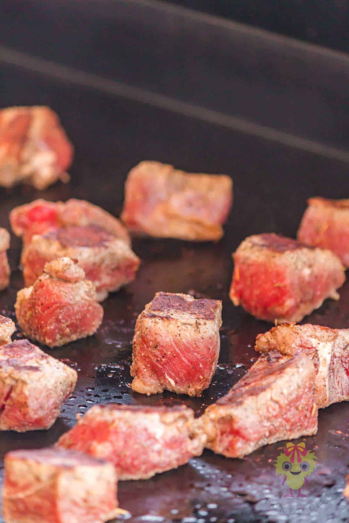 Showing how the NY strip steak bites are seared beautifully on the flat top griddle. You can see how flipping each piece to an empty spot on the griddle is giving an even sear to both sides.