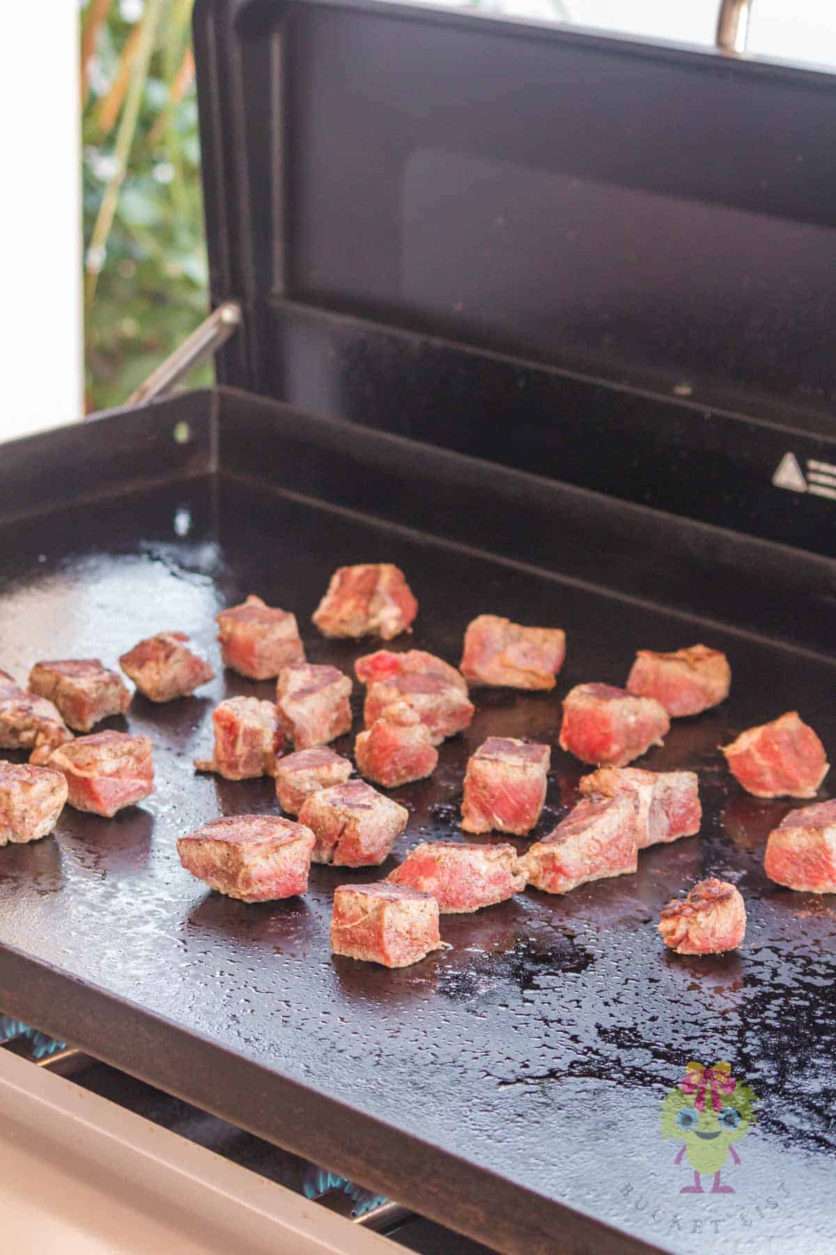 Showing the importance of preheating the griddle and stabilizing it to the desired temperature before adding the steak bites. You can see there is enough room to flip each bite to an empty place on the flat top griddle. This is key for even searing.