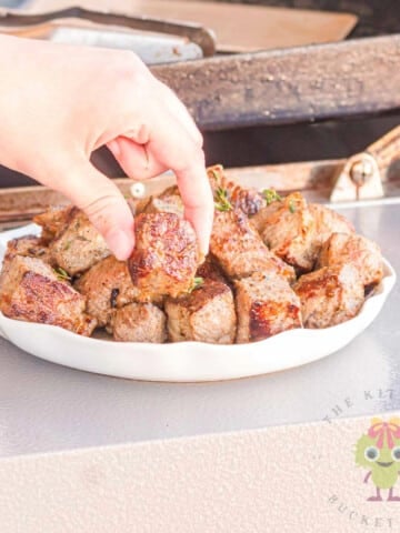 A picture of me stealing a garlic steak bite from the serving bowl. Using the NY strip steak, pantry staples for the dry rub, and finishing with the garlic butter bath really makes these steak bites my go-to for a quick steak night.