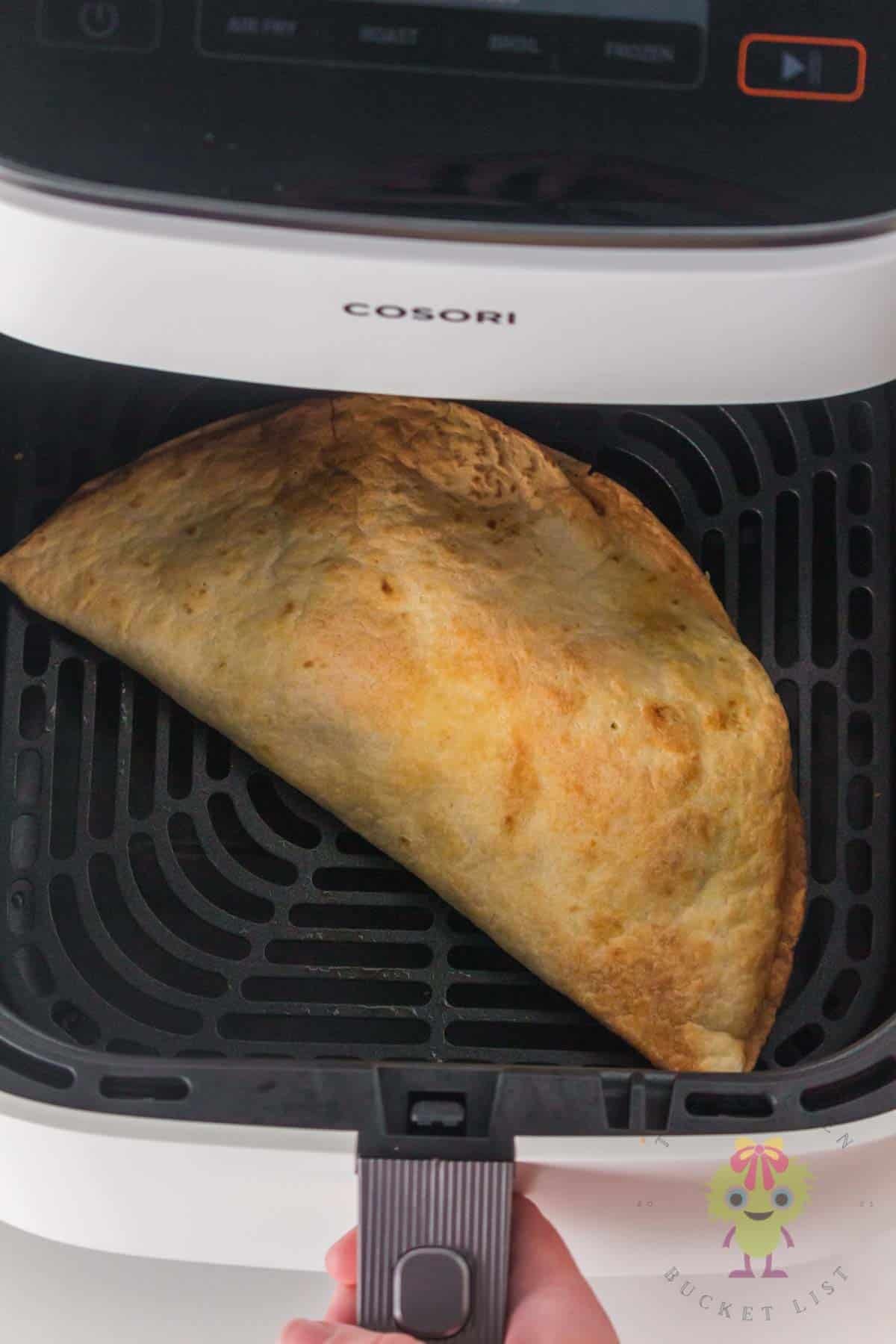 Golden crispy air fryer Mississippi ground beef quesadilla in the air fryer basket being pulled out, perfectly cooked and ready to serve.
