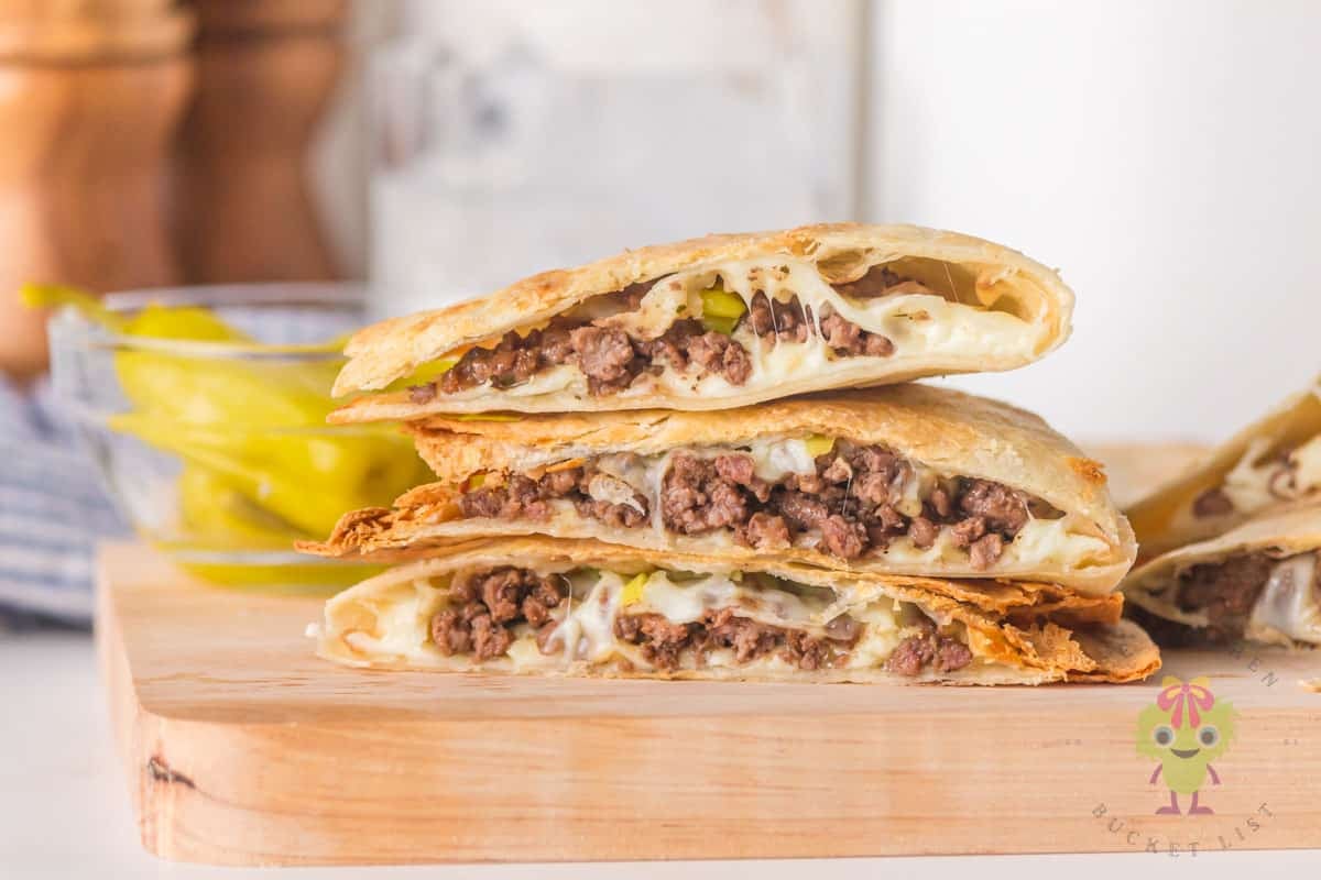 Stack of sliced air fryer Mississippi ground beef quesadillas on a wooden cutting board showing the cheesy beef filling.