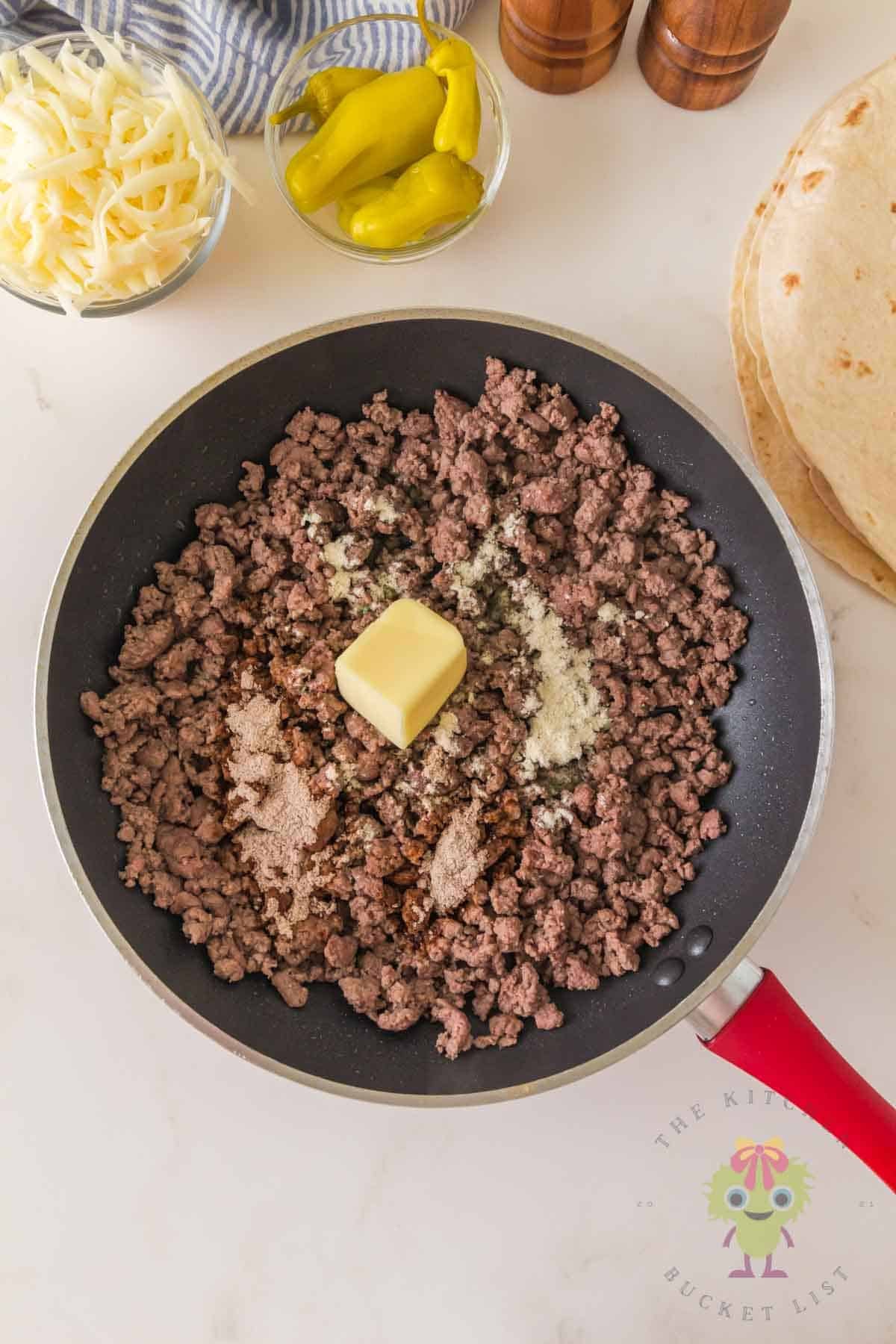 Skillet filled with Mississippi seasoning, ground beef, and butter, ready to be melted with pepperoncini peppers to make that iconic Mississippi beef flavor.
